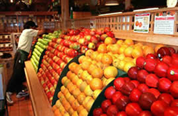 An image of a large fruit stand, with oranges and various types of apples for sale.